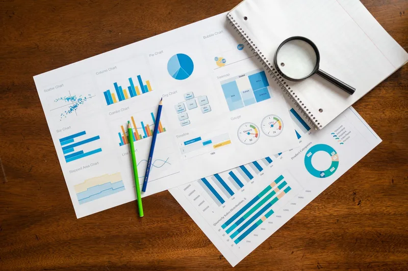 Overhead view of financial charts and data analysis materials on a desk, representing the comparison process when evaluating Excel against dedicated inventory management software