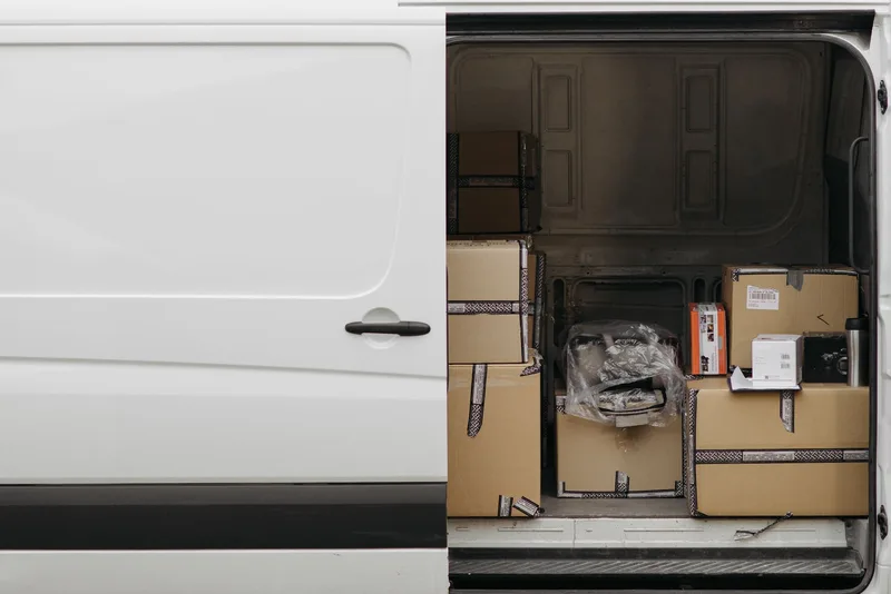Open delivery van packed with sealed shipping boxes ready for courier pickup
