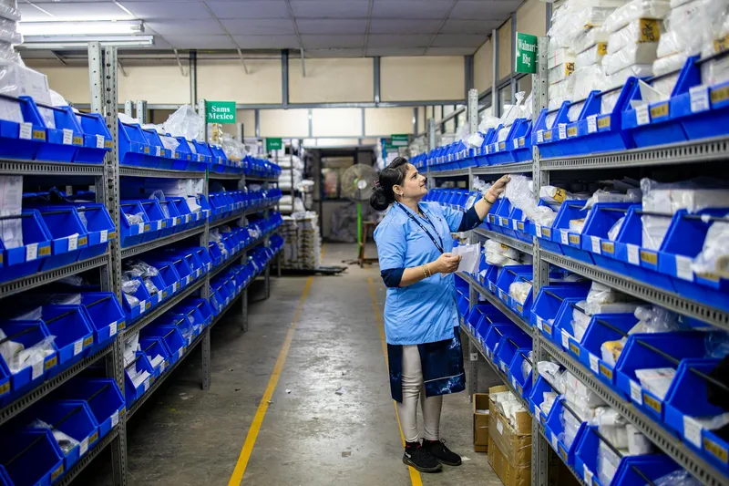 A warehouse worker organizing inventory on industrial shelves, representing systematic warehouse management workflow