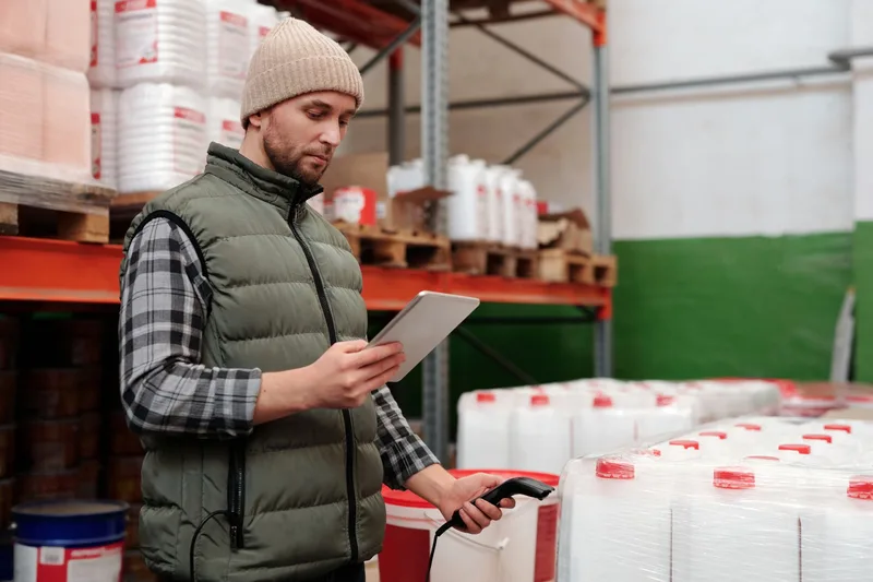 Man managing inventory with tablet in a Philippine warehouse, focusing on pick accuracy