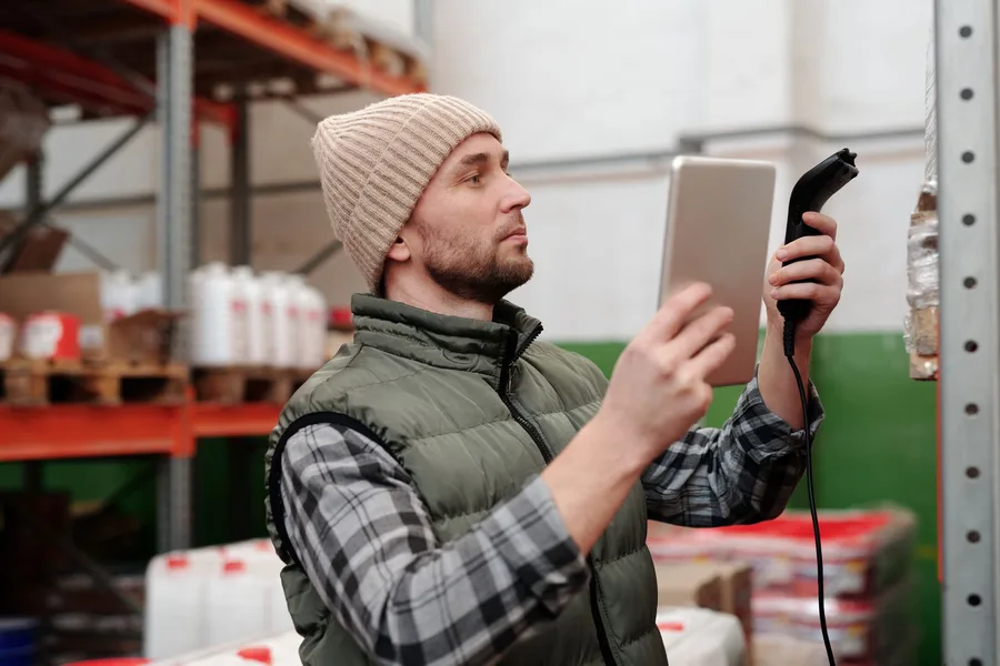 Warehouse worker using a handheld scanner to manage inventory in a fulfillment center
