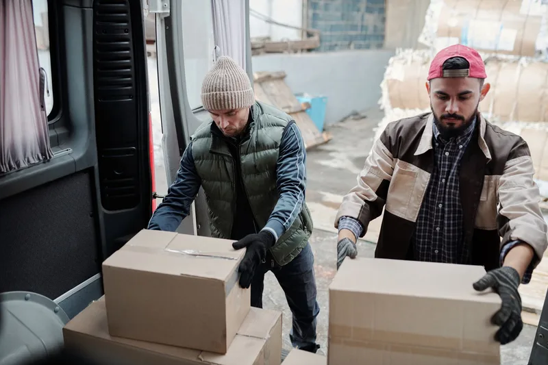Two warehouse workers loading packages for delivery