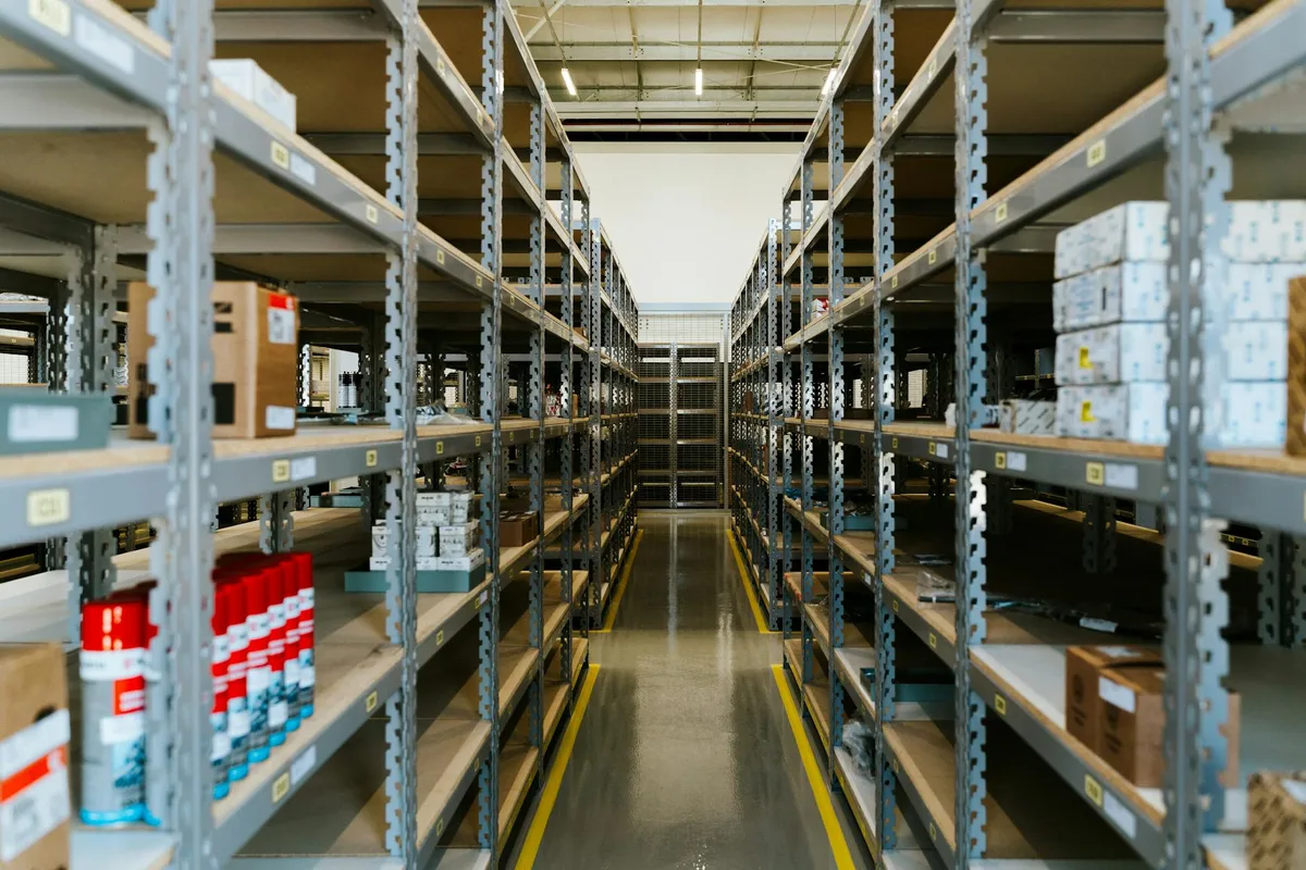Organised warehouse with metal shelving and stored merchandise representing a WMS warehouse management system for ecommerce